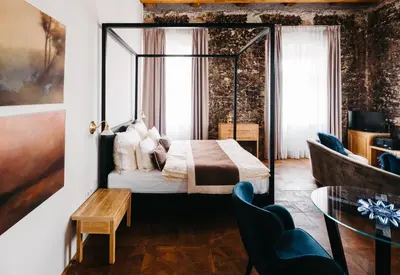 a bedroom with a canopy bed and a table and chairs at Boutique hotel Corso in Řevnice