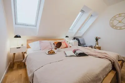 a bedroom with a bed with pink and white pillows at Prague Days - Minimalistic Studio with Netflix and View to National Museum in Prague