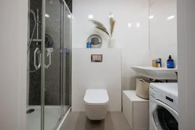 a bathroom with a shower and a toilet and a washing machine at Prague Days - Minimalistic Studio with Netflix and View to National Museum in Prague