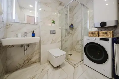 a bathroom with a toilet sink and a washing machine at Prague Days - Minimalistic Studio with Netflix and View to National Museum in Prague