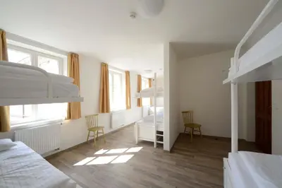 a bedroom with two bunk beds and two chairs at Safestay Prague Charles Bridge in Prague