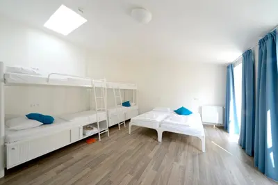 a bedroom with white bunk beds and blue curtains at Safestay Prague Charles Bridge in Prague