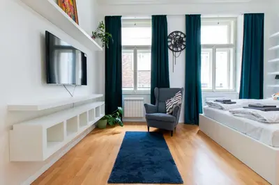 a bedroom with a bed with a blue rug and a chair at Stay Inn Apartments Stepanska in Prague