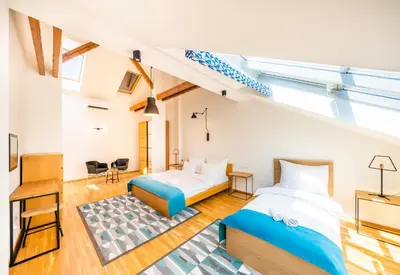 a loft bedroom with two beds and a staircase at 5BR+3.5BT Wilson Central apt. in Prague