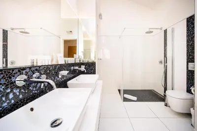 a white bathroom with two sinks and a shower at 5BR+3.5BT Wilson Central apt. in Prague