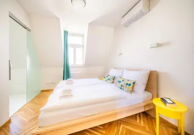 a bedroom with a white bed and a yellow stool at Luxurious Woodrow Wilson apt in Prague centre in Prague