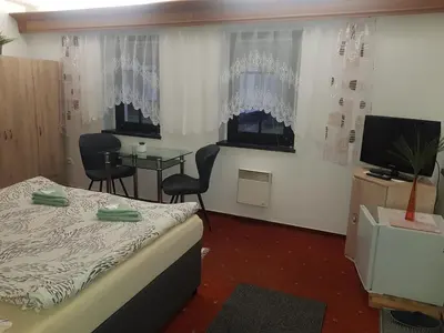 a room with a bed and a table and a television at U Královny Dagmar in Karlštejn