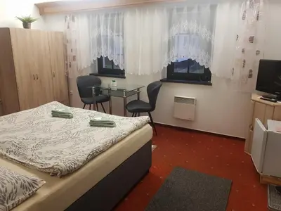 a bedroom with a bed and a table and chairs at U Královny Dagmar in Karlštejn