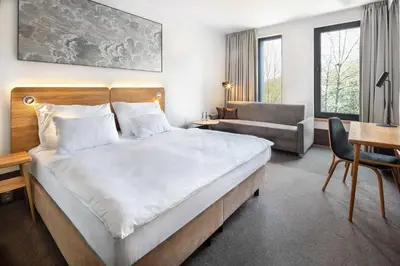 a hotel room with a large bed and a chair at Hotel Golf Prague in Prague
