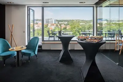 a restaurant with a table and chairs and a large window at Hotel Golf Prague in Prague