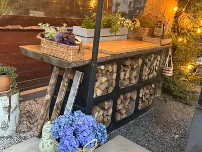 a table with a pile of fire wood and flowers at Camping Matyáš in Vrané nad Vltavou