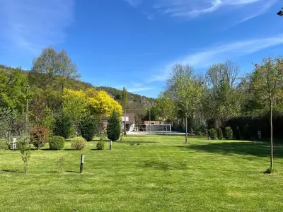 a green field with trees and a building in the background at Camping Matyáš in Vrané nad Vltavou