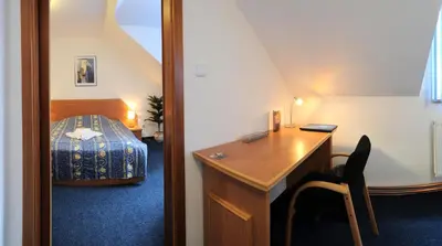 a small room with a desk and a bed at Wellness Hotel Svoboda in Rakovník