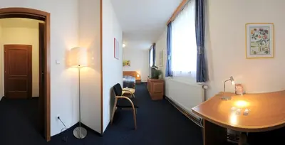 a room with a desk and a table and a window at Wellness Hotel Svoboda in Rakovník