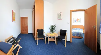 a room with a table and chairs and a bed at Wellness Hotel Svoboda in Rakovník