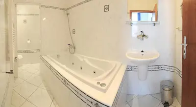 a white bathroom with a tub and a sink at Wellness Hotel Svoboda in Rakovník