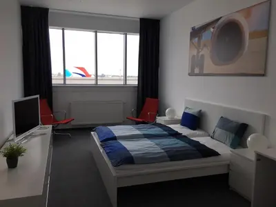 a bedroom with a bed and two chairs and a television at AeroRooms in Prague