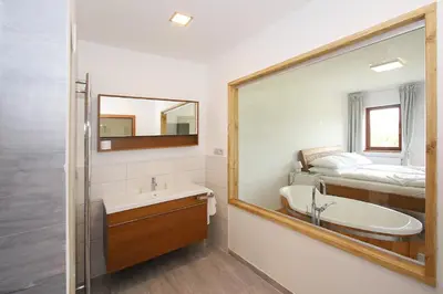 a bathroom with a sink and a mirror and a bed at Areal Botanika in Unhošť