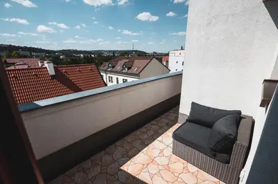 a chair on a balcony with a view of a city at POINT flat, beautiful view from terrace to Prague Castle in Prague
