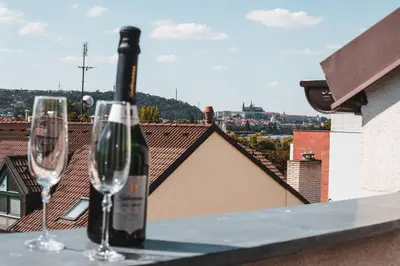 two wine glasses and a bottle of wine on a ledge at POINT flat, beautiful view from terrace to Prague Castle in Prague