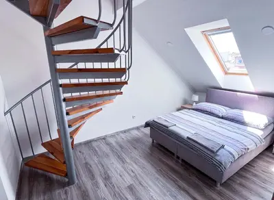 a bedroom with a bed and a spiral staircase at Minihotel Vitex in Prague