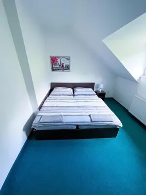 a bed in a white room with a green floor at Minihotel Vitex in Prague
