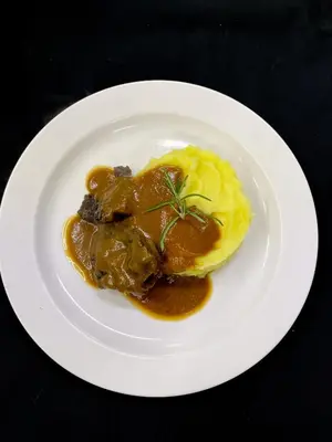 a plate of food with meat and gravy and eggs at Penzion Na Vošverku in Čelákovice