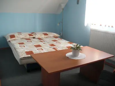 a bedroom with a bed and a wooden table at Pension Olga in Klecany