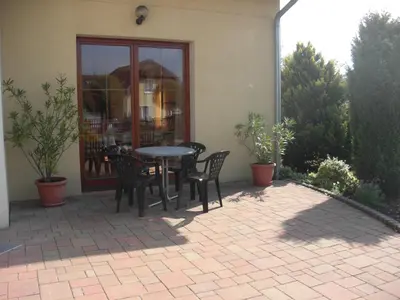 a patio with a table and chairs in front of a building at Pension Olga in Klecany