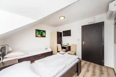 a bedroom with two beds and a desk at Nová Hospoda - Hotel & Restaurant in Prague