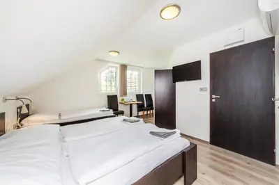 a bedroom with a large white bed and a table at Nová Hospoda - Hotel & Restaurant in Prague