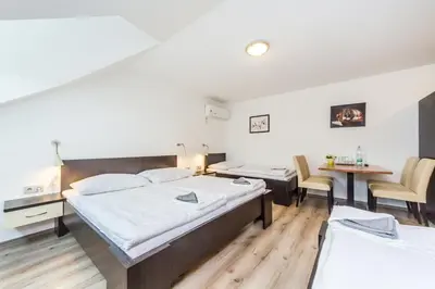 a hotel room with two beds and a table and chairs at Nová Hospoda - Hotel & Restaurant in Prague