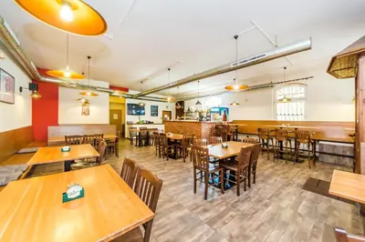 an empty restaurant with wooden tables and chairs at Nová Hospoda - Hotel & Restaurant in Prague