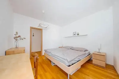 a white bedroom with a bed and a table at Apartment Tereza in Prague