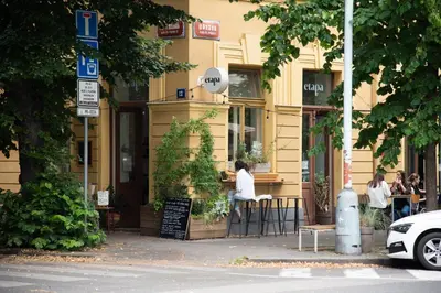 a woman sitting at a table in front of a building at Apartment Tereza in Prague