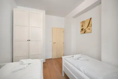 two beds in a room with white walls and wooden floors at Downtown Residence in Prague