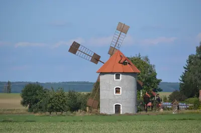 a windmill with an orange roof on a field at Adela´s Czech Village House in Všejany