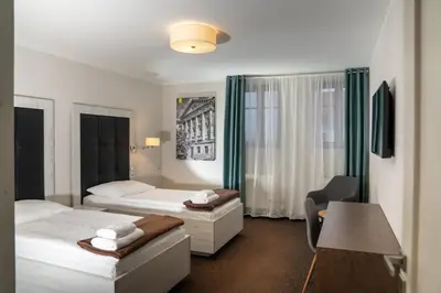 a hotel room with two beds and a desk at Hotel Grunt in Mladá Boleslav