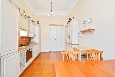 a kitchen with white cabinets and a wooden table at Open Gate in Prague