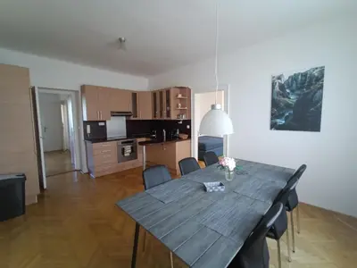 a dining room table with chairs and a kitchen at Vila Malvazinky in Prague