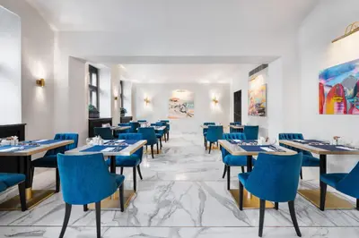 a dining room with tables and blue chairs at Áurea Legends by Eurostars Hotel Company in Prague