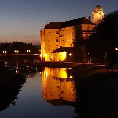 a building with its reflection in the water at night at Apartman Harmonia Poděbrady 60m2 in Poděbrady
