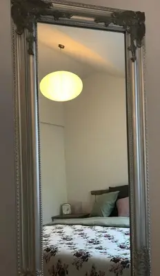 a mirror reflecting a bedroom with a bed and a light at Apartman Harmonia Poděbrady 60m2 in Poděbrady