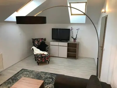 a living room with a tv and a chair at Apartman Harmonia Poděbrady 60m2 in Poděbrady
