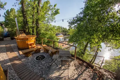 a wooden deck with a fire pit next to a river at Prague Bay Houseboats in Prague