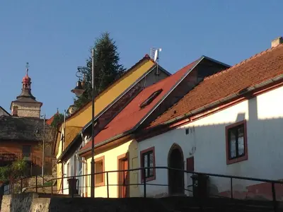 a white building with a red roof and a church at Apartmány č.p. 9 in Kouřim