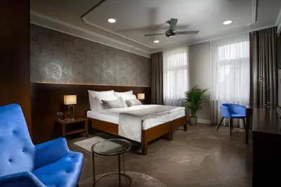 a bedroom with a bed and a blue chair at Hotel Anna in Beroun