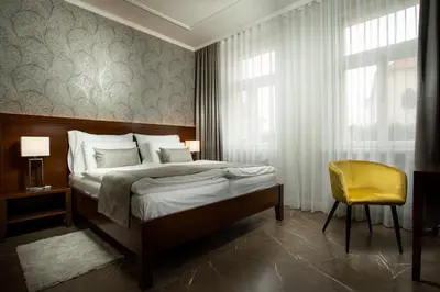 a bedroom with a bed and a yellow chair at Hotel Anna in Beroun