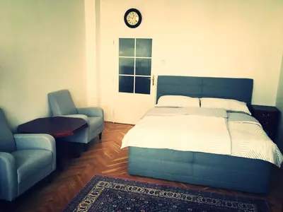 a bedroom with a bed and a chair and a clock at Apartment Anna Vysehrad in Prague