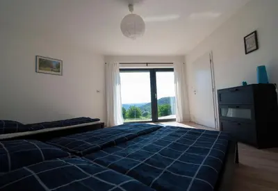 a bedroom with a blue bed and a large window at Wellness bungalov - vodní nádrž Slapy - 40km od Prahy in Nečín
